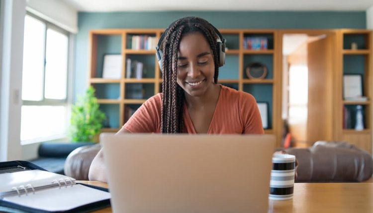 Retrato de uma mulher em uma videochamada com laptop e fones de ouvido enquanto trabalhava em casa